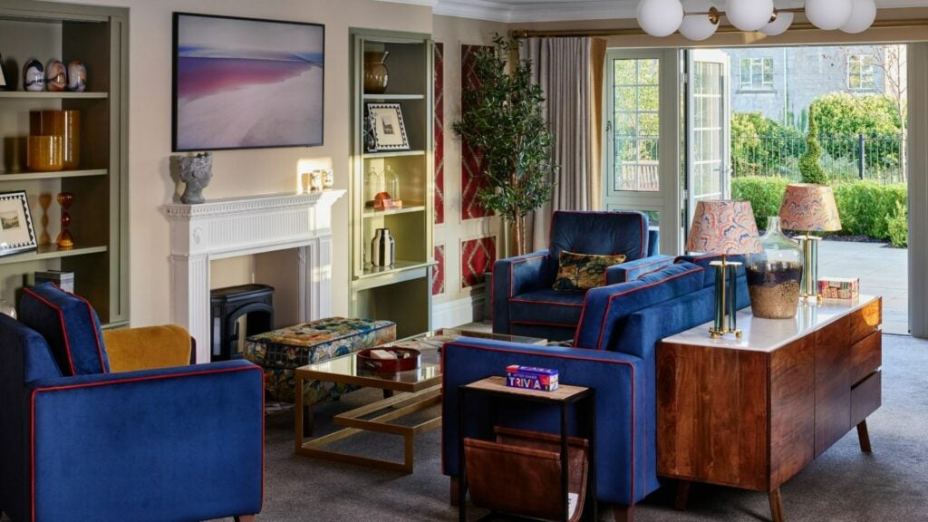 Modern lounge with blue chairs and fireplace in a luxury dementia care home.