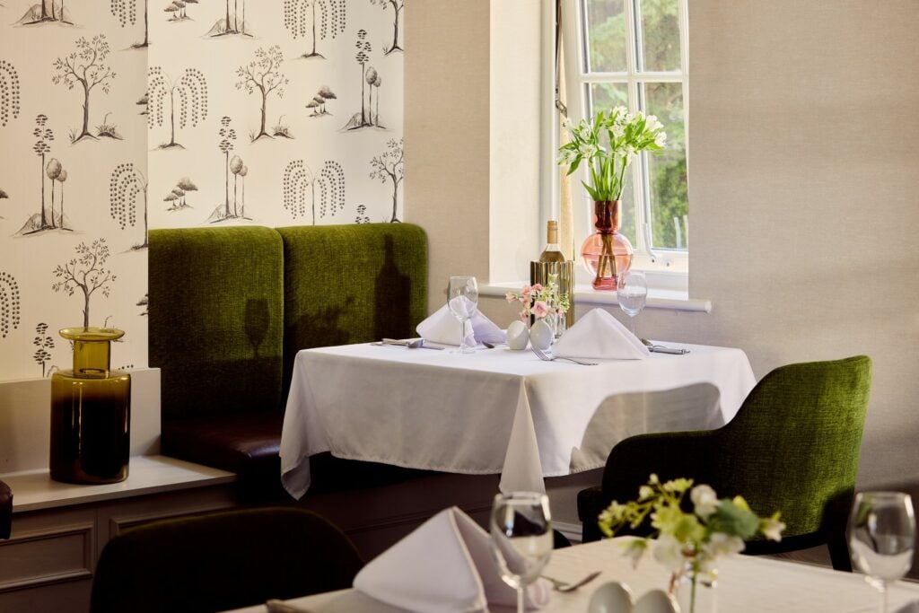 Elegant restaurant table with green chairs and floral decor.