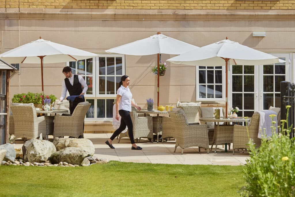 Waiters serving in a sunny outdoor restaurant patio.