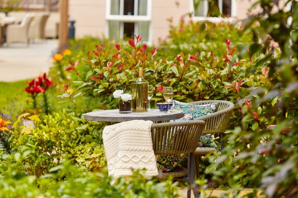 Cosy garden table set for two with wine.