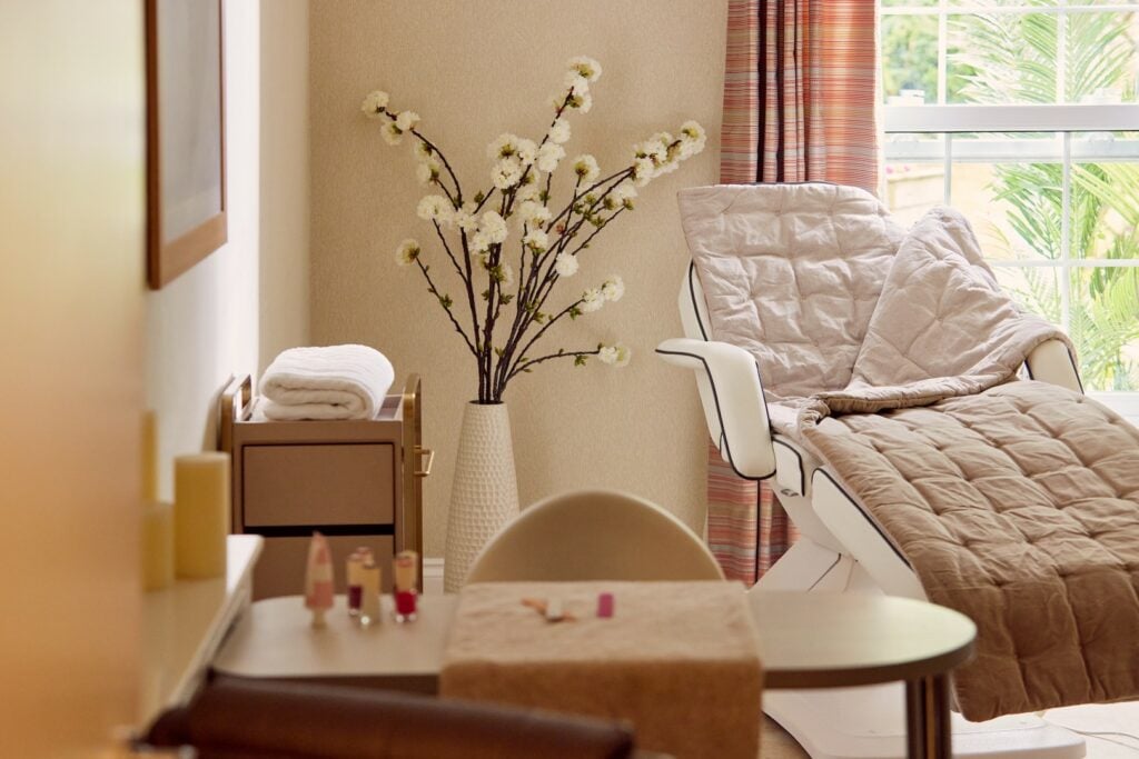 Cosy spa room with reclining chair and flowers.