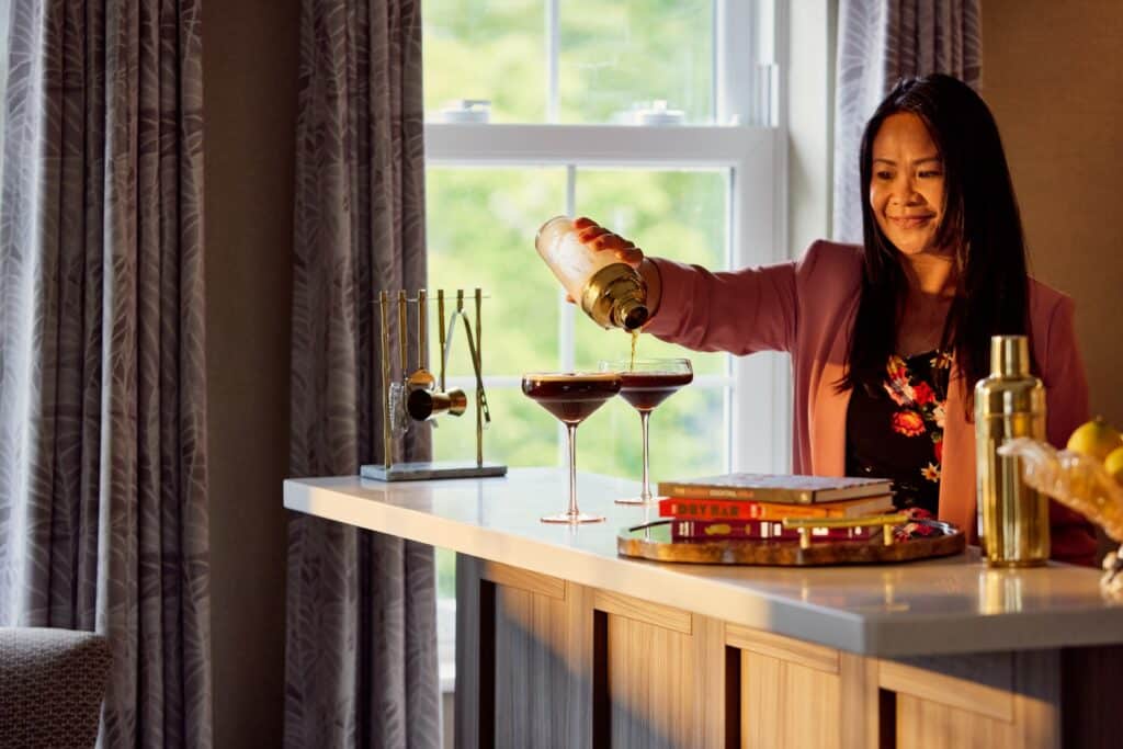 Woman pouring cocktails at home bar.