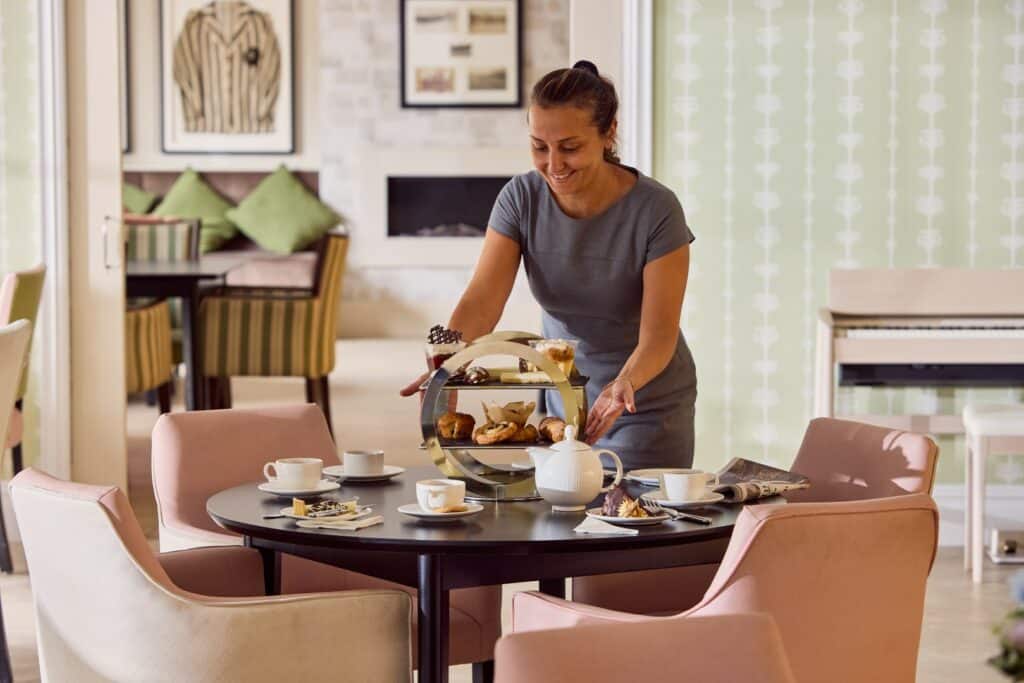 Woman arranging afternoon tea in cosy sitting room.