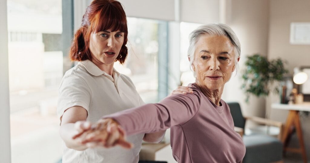 Instructor helps senior woman with arm exercise