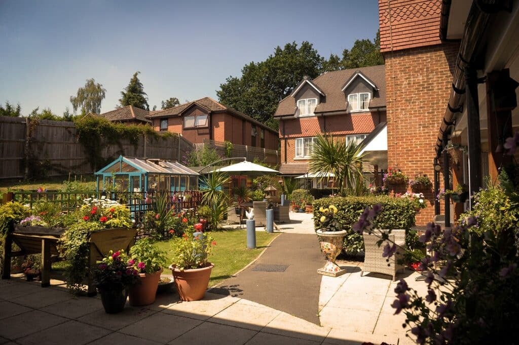 Sunny garden view with colourful flowers, buildings.