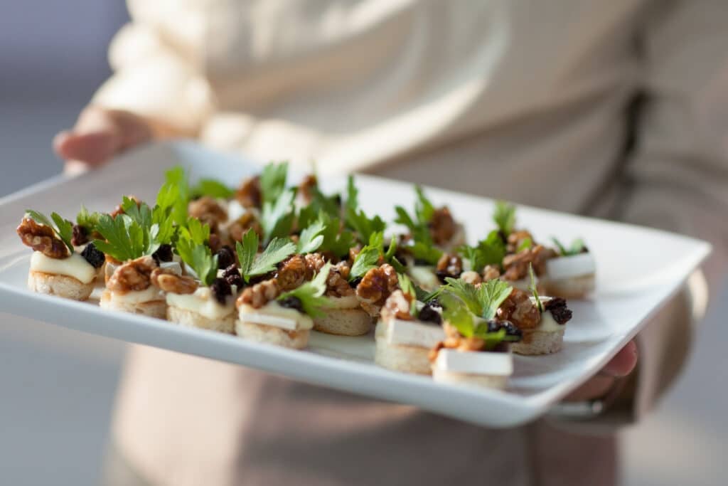 Serving platter of appetisers with cheese, nuts, herbs.