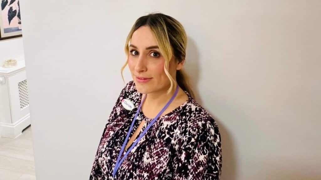 Person in patterned dress with lanyard, indoors.