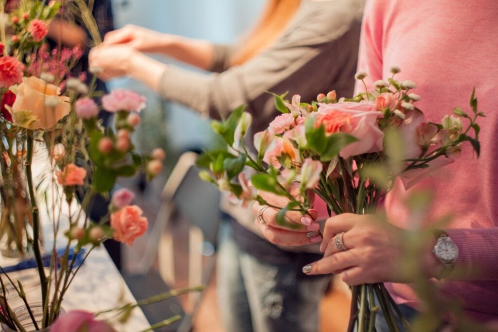 Hands arranging pink bouquets indoors