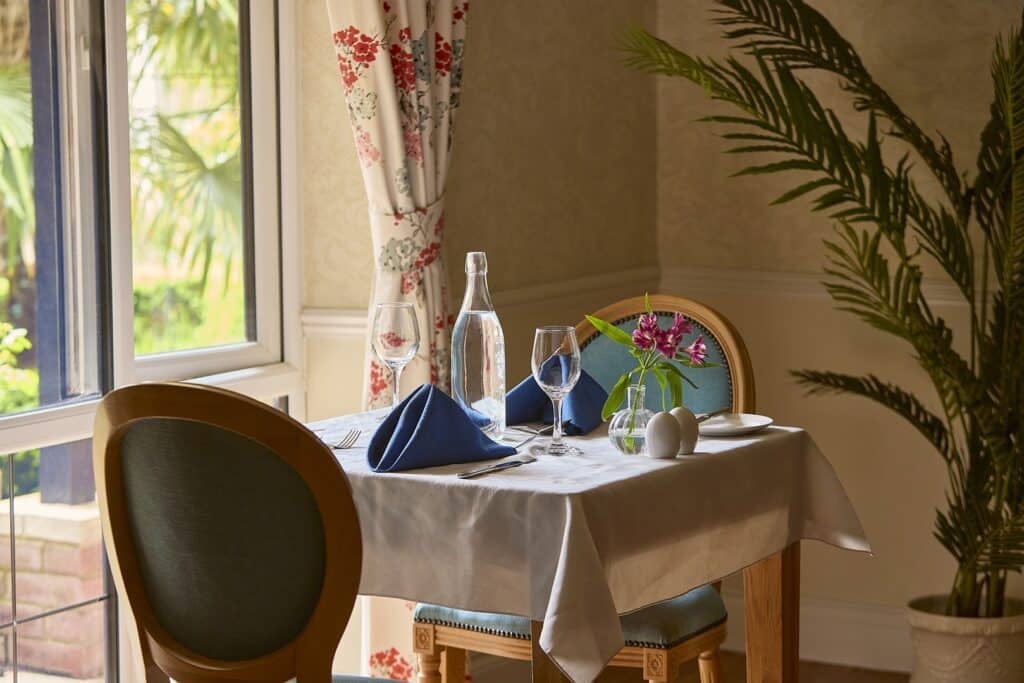 Elegant dining table by window with wine glasses.