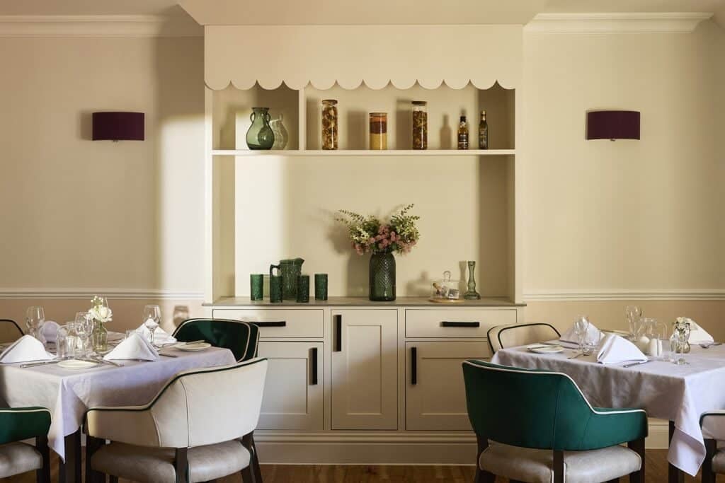 Elegant dining room with set tables and decorative shelves.