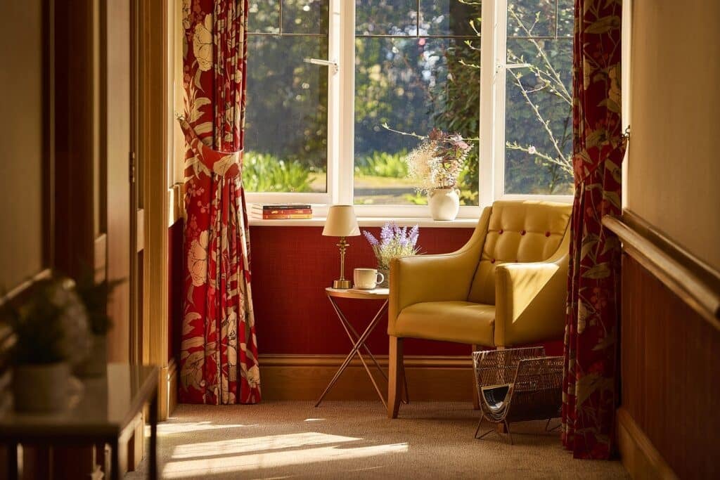 Cosy reading nook with yellow chair and window view.