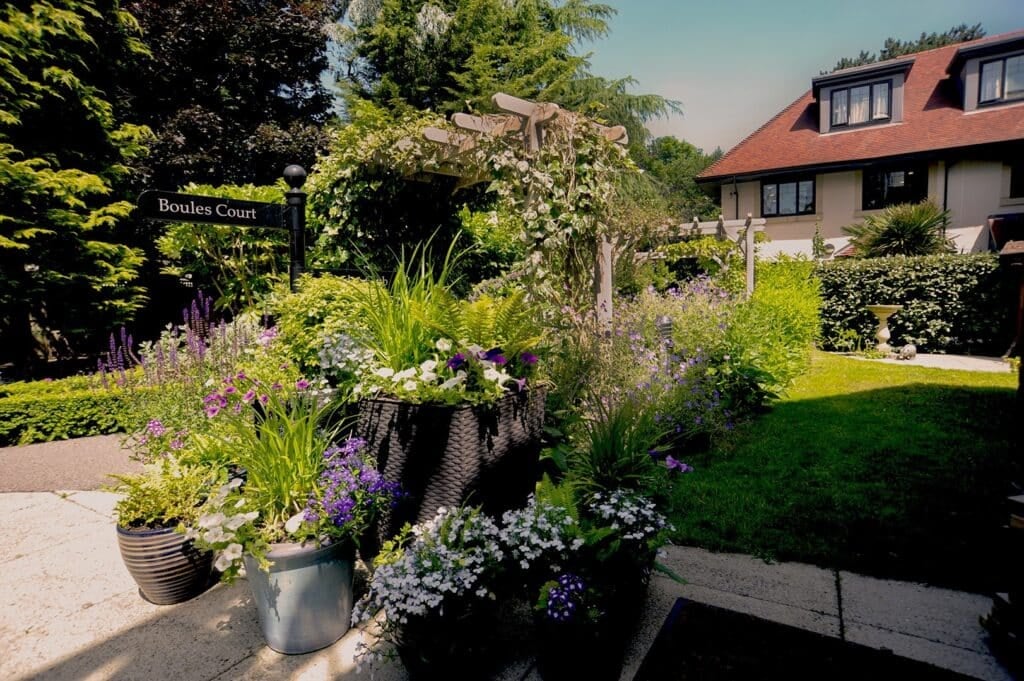 Lush garden beside a white house.