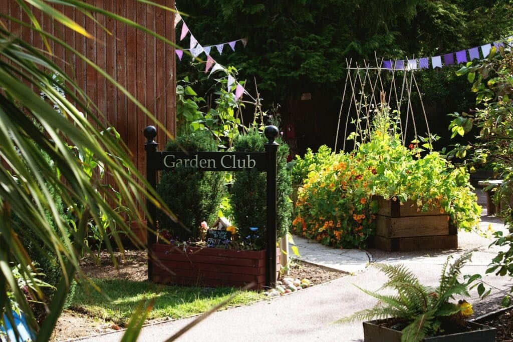 Garden club entrance with vibrant plants and bunting.