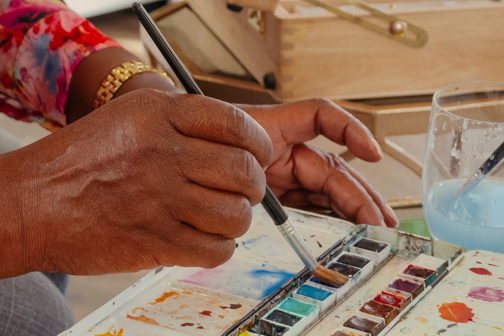Person painting with watercolours and brush.