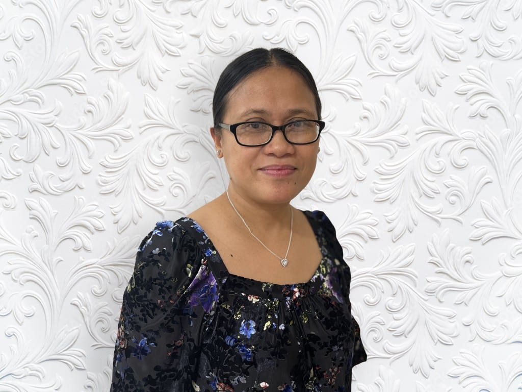 Woman in floral dress with embossed wallpaper background.
