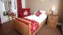 Cosy single room with red decor and garden view.