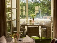 Cosy outdoor dining table with flowers and sunny view.