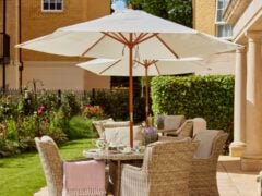 Outdoor patio with wicker furniture and large white parasol.