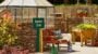 Outdoor garden club area with bench, plants, and greenhouse.