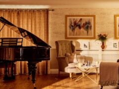 Elegant living room with grand piano and armchairs.
