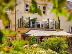 Beautiful hotel with balcony in lush garden setting.