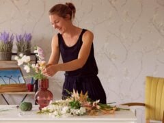 Woman arranging flowers in a vase indoors.