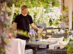 Woman serving wine at outdoor garden table.
