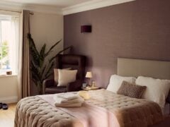 Cosy hotel room with double bed and armchair.