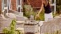 Woman pouring wine in garden seating area.