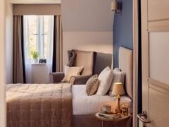 Cosy bedroom with armchair, lamp, and garden view.