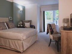Modern care home room with desk and garden patio area.