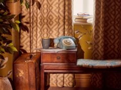 Vintage phone on wooden table near curtained window.