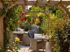 Garden patio with table and chairs under pergola.