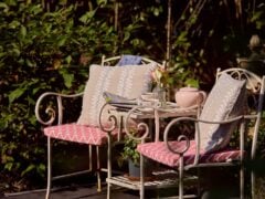 Cosy garden seating with cushions and a teapot.