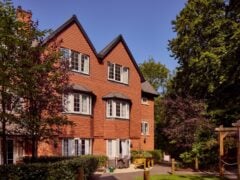 Charming red-brick building surrounded by lush greenery.