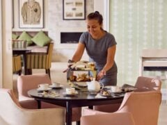 Woman arranging afternoon tea in cosy sitting room.