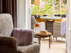 Cosy armchair by open doors to garden patio.