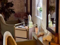 Beauty products on dressing table with mirror reflection.