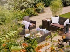 Cosy garden patio with wicker furniture and plants.