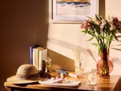 Sunlit table with books, flowers, and hat.