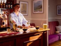 Man enjoying drinks at home bar with jukebox.