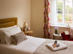 Cosy bedroom with window view, floral curtains, bedside lamp.