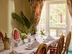 Elegant dining room with table settings and flowers.