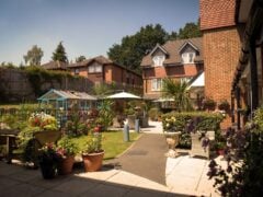 Sunny garden view with colourful flowers, buildings.