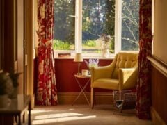 Cosy reading nook with yellow chair and window view.