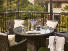 Patio with table, chairs, wine, and flowers.
