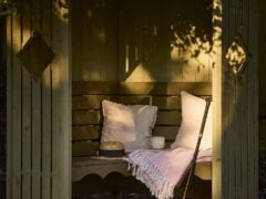 Cosy garden nook with cushions and a mug.