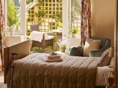 Bright bedroom with bed, armchair, and garden view