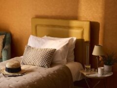 Cosy bedroom with hat on bed and side table.