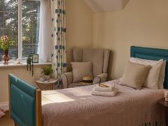 Cosy bedroom with single bed and armchair.